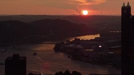 4K aerial stock footage setting sun seen while flying by skyscrapers, reveal West End Bridge, Pittsburgh, Pennsylvania, sunset Aerial Stock Footage | AX108_061E
