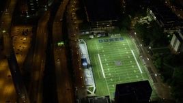 4K aerial stock footage orbiting Arthur J. Rooney Athletic Field and tilt up to reveal the city, Pittsburgh, night Aerial Stock Footage | AX108_191E