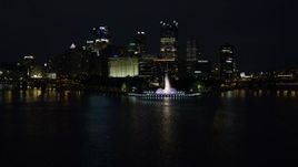 4K aerial stock footage descend to river, fly over Point State Park toward skyscrapers, Downtown Pittsburgh, night Aerial Stock Footage | AX108_217E