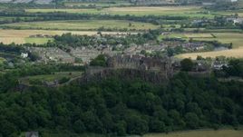 5.5K aerial stock footage of Stirling Castle atop a tree-covered hill in Scotland Aerial Stock Footage | AX109_019E