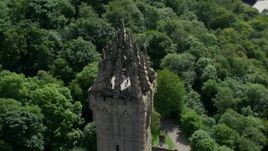 5.5K aerial stock footage of orbiting top of iconic Wallace Monument surrounded in trees, Stirling, Scotland Aerial Stock Footage | AX109_052E