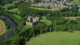 5.5K aerial stock footage of Doune Castle and River Teith among trees, Scotland Aerial Stock Footage | AX109_074E
