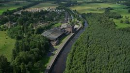 5.5K aerial stock footage of approaching a riverfront factory by River Teith, Doune, Scotland Aerial Stock Footage | AX109_080