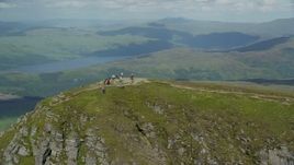 5.5K aerial stock footage of flyby hikers on Ben Lomond mountain peak in the Scottish Highlands, Scotland Aerial Stock Footage | AX110_052