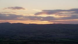 5.5K aerial stock footage of setting sun behind clouds over Scottish Highlands, Scotland Aerial Stock Footage | AX112_152E