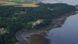 5.5K aerial stock footage of Culzean Castle by trees and Firth of Clyde, Maybole, Scotland Aerial Stock Footage | AX113_054E