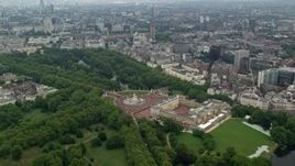 5.5K aerial stock footage orbit Buckingham Palace, London Eye and Parliament in the distance, London, England Aerial Stock Footage | AX114_212