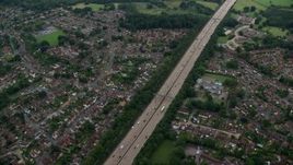 5.5K aerial stock footage of flying over M25 Freeway past farm fields, Addlestone, England Aerial Stock Footage | AX114_355E