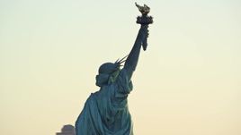 5.5K aerial stock footage of a close orbit around the back of the Statue of Liberty at sunrise in New York Aerial Stock Footage | AX118_110E