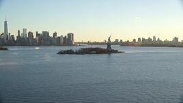 5.5K aerial stock footage wide view of Statue of Liberty, and skylines of Brooklyn and Lower Manhattan at sunrise in New York Aerial Stock Footage | AX118_119E