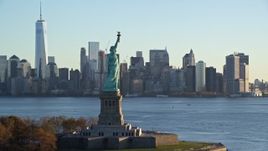 5.5K aerial stock footage approach the Statue of Liberty at sunrise in New York, and flyby for a view of Lower Manhattan skyline Aerial Stock Footage | AX118_131E