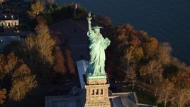 5.5K aerial stock footage approach and tilt to bird's eye of the Statue of Liberty at sunrise in New York Aerial Stock Footage | AX118_144E