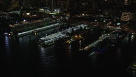 5.5K aerial stock footage fly away from and orbit warships and a cruise ship in Hell's Kitchen docks at Night, Midtown, New York City Aerial Stock Footage | AX123_009E