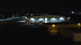 5.5K aerial stock footage of civilian jets parked outside a hangar at Night at Republic Airport in Farmingdale, New York Aerial Stock Footage | AX123_191E