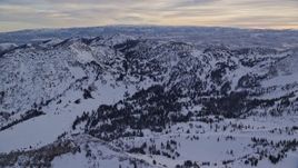 5.5K aerial stock footage pan across and approach snowy winter mountains at sunrise in Wasatch Range, Utah Aerial Stock Footage | AX124_074E