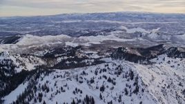 5.5K aerial stock footage of flying over snowy mountain ridge in winter at sunrise in Wasatch Range, Utah Aerial Stock Footage | AX124_084E