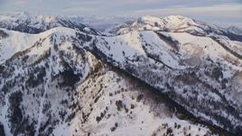 5.5K aerial stock footage tilt from mansions and roads to approach snowy ridge in winter at sunrise, Wasatch Range, Utah Aerial Stock Footage | AX124_096E