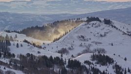 5.5K aerial stock footage of snowdrifts blowing off a mountain at sunrise in the Wasatch Range, Utah Aerial Stock Footage | AX124_102