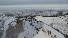 5.5K aerial stock footage of flying over snowy mountains in Utah's Wasatch Range at sunrise Aerial Stock Footage | AX124_140