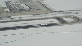 5.5K aerial stock footage track airliner landing at Salt Lake City International Airport with winter snow in Utah Aerial Stock Footage | AX125_011