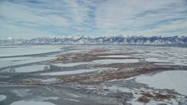 5.5K aerial stock footage of snowy Wasatch Range mountains and frozen marshlands in winter, Utah Aerial Stock Footage | AX125_027E