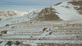 5.5K aerial stock footage fly over rocky ground and snow up the slopes of mountains in winter, Antelope Island, Utah Aerial Stock Footage | AX125_086E