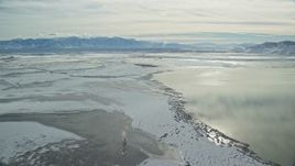 5.5K aerial stock footage of a view of frozen marshland to Wasatch Range in winter, Utah Aerial Stock Footage | AX125_102E