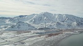 5.5K aerial stock footage approach Kennecott Smokestack and Oquirrh Mountains in winter, Utah Aerial Stock Footage | AX125_106