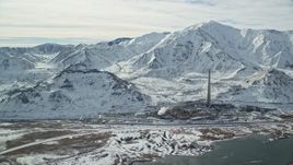 5.5K aerial stock footage approach Kennecott Smokestack by Oquirrh Mountains in winter, Magna, Utah Aerial Stock Footage | AX125_109