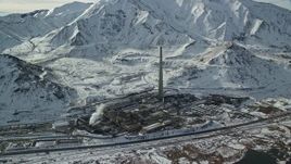 5.5K aerial stock footage of approaching tall factory smoke stack and Oquirrh Mountains in wintertime, Magna, Utah Aerial Stock Footage | AX125_110E
