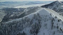 5.5K aerial stock footage approach snowdrift blowing over trees on a mountain peak slope, Oquirrh Mountains, Utah Aerial Stock Footage | AX125_201E
