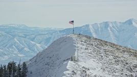 5.5K aerial stock footage approach American flag waving atop a snowy peak in winter, Oquirrh Mountains, Utah Aerial Stock Footage | AX125_210E