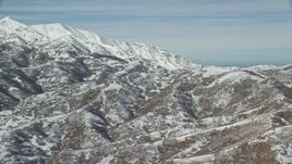 5.5K aerial stock footage of flying by mountains with light snow near larger white peaks in winter, Oquirrh Mountains, Utah Aerial Stock Footage | AX125_284E