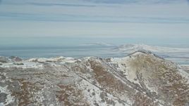 5.5K aerial stock footage of Great Salt Lake seen from a snowy ridge in the Oquirrh Mountains, Utah Aerial Stock Footage | AX125_286