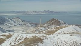 5.5K aerial stock footage of tall Kennecott Smokestack seen from snowy mountains in winter, Magna, Utah Aerial Stock Footage | AX125_291