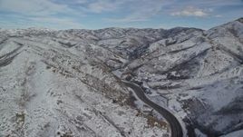 5.5K aerial stock footage of following Interstate 80 with light traffic through Wasatch Range with winter snow, Utah Aerial Stock Footage | AX126_070E