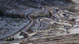 5.5K aerial stock footage orbit the winding luge and bobsled track at Utah Olympic Park with winter snow, Park City Aerial Stock Footage | AX126_102