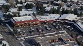 5.5K aerial stock footage of orbiting shops at a small town strip mall with winter snow in Park City, Utah Aerial Stock Footage | AX126_164