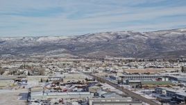 5.5K aerial stock footage of mountains with light snow seen from warehouse buildings in winter, Heber City, Utah Aerial Stock Footage | AX126_217