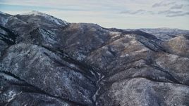 5.5K aerial stock footage of crossing snowy mountains in wintertime at sunset, Wasatch Range, Utah Aerial Stock Footage | AX127_013E