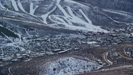 5.5K aerial stock footage of the small town of Park City in the shadow of snowy mountain in winter at sunset, Utah Aerial Stock Footage | AX127_020E