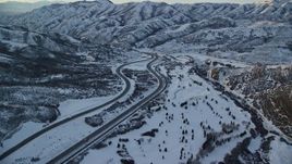 5.5K aerial stock footage approach and follow I-80 with light traffic through a wintery Wasatch Range pass at sunset, Utah Aerial Stock Footage | AX127_053E