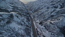 5.5K aerial stock footage follow I-80 through Wasatch Range with winter snow at sunset, Utah Aerial Stock Footage | AX127_056E
