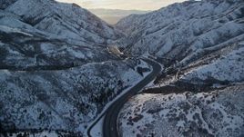 5.5K aerial stock footage of a curve in the freeway through a snowy Wasatch Range mountain pass at sunset, Utah Aerial Stock Footage | AX127_060E