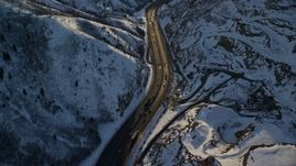 5.5K aerial stock footage of cars and big rigs traveling through a frozen mountain pass at sunset, Wasatch Range, Utah Aerial Stock Footage | AX127_068E