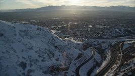 5.5K aerial stock footage approach Salt Lake City suburbs from snowy Wasatch Range mountains at sunset, Utah Aerial Stock Footage | AX127_073