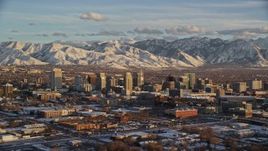 5.5K aerial stock footage a view of Downtown Salt Lake City and distant snow mountains at sunset in winter, Utah Aerial Stock Footage | AX127_145E