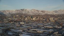 5.5K aerial stock footage of Downtown Salt Lake City's tall buildings and distant snow mountains at sunset in winter, Utah Aerial Stock Footage | AX127_154