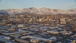 5.5K aerial stock footage of Downtown Salt Lake City's tall buildings and distant snow mountains at sunset in winter, Utah Aerial Stock Footage | AX127_154E