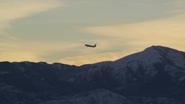 5.5K aerial stock footage of tracking an airliner soaring over snow mountains at sunset in winter, Salt Lake City, Utah Aerial Stock Footage | AX127_173